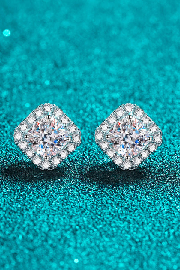 Square clear-stone cluster stud earrings positioned diagonally on a teal background