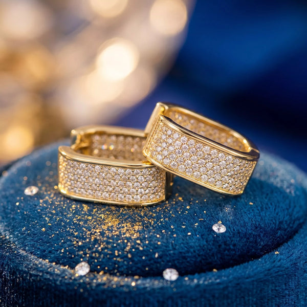 Gold-tone square hoop earrings with clear stones on blue fabric