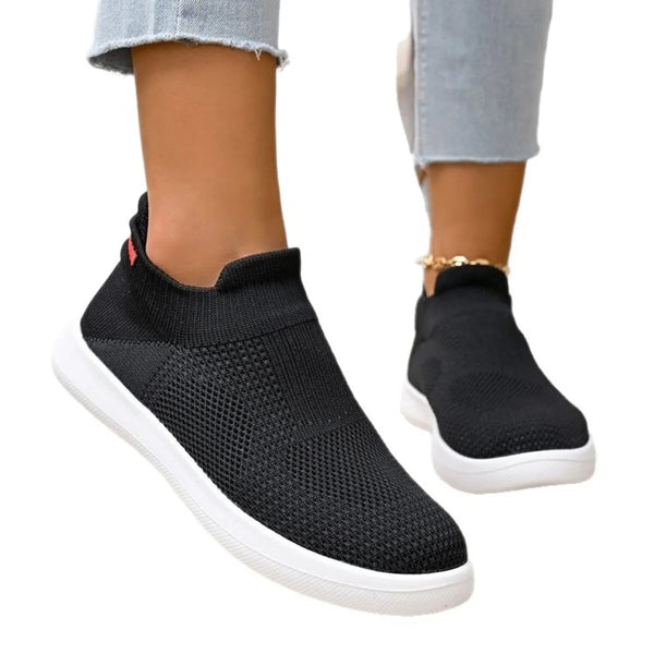 Pair of black mesh slip-on sneakers worn with jeans