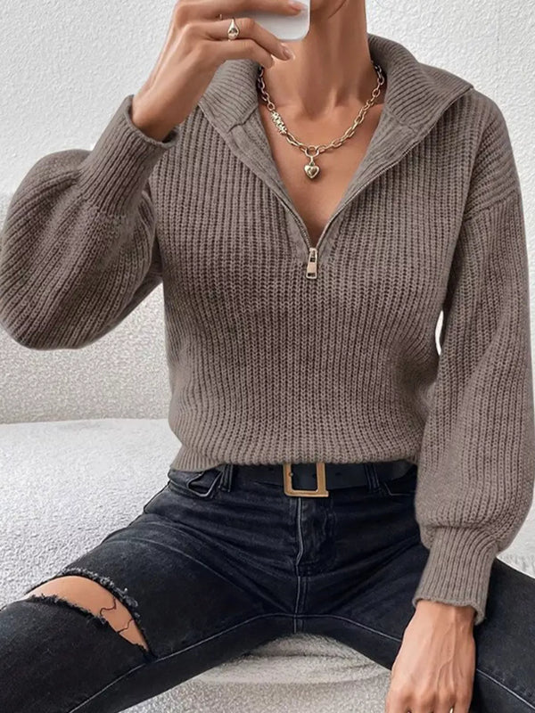 Seated model in taupe quarter-zip sweater showing the open collar and ribbed cuffs