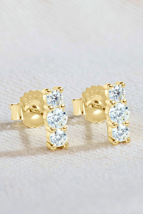 Pair of three-stone vertical moissanite studs on textured surface