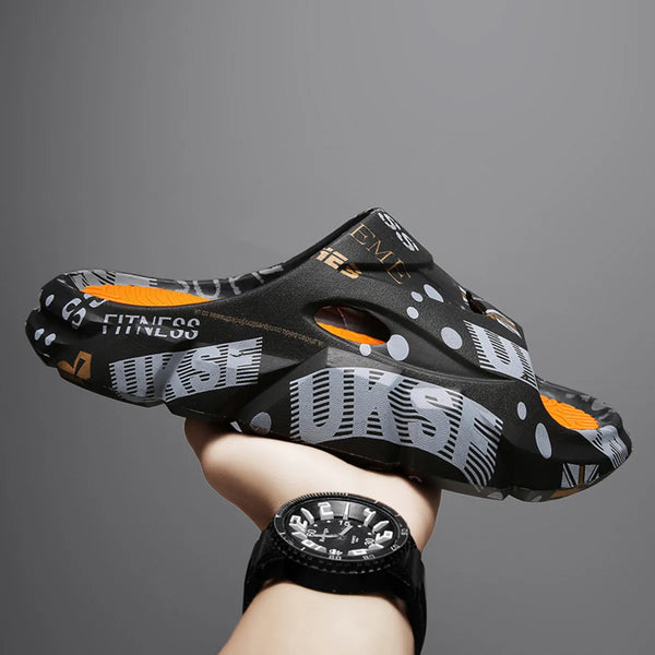 Black printed platform slide held in a hand, showing orange footbed and oval side opening