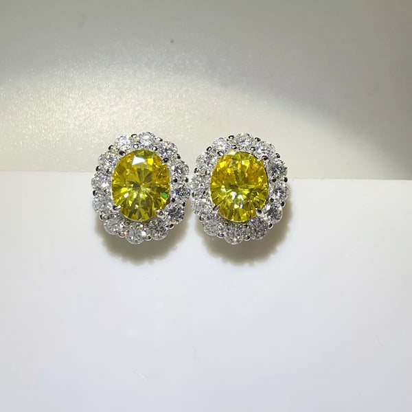 Pair of yellow oval moissanite stud earrings with clear halo stones.