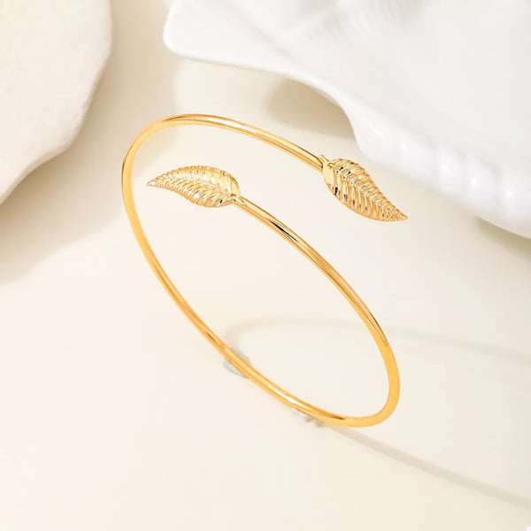 Gold-tone leaf open cuff bracelet displayed against pale fabric