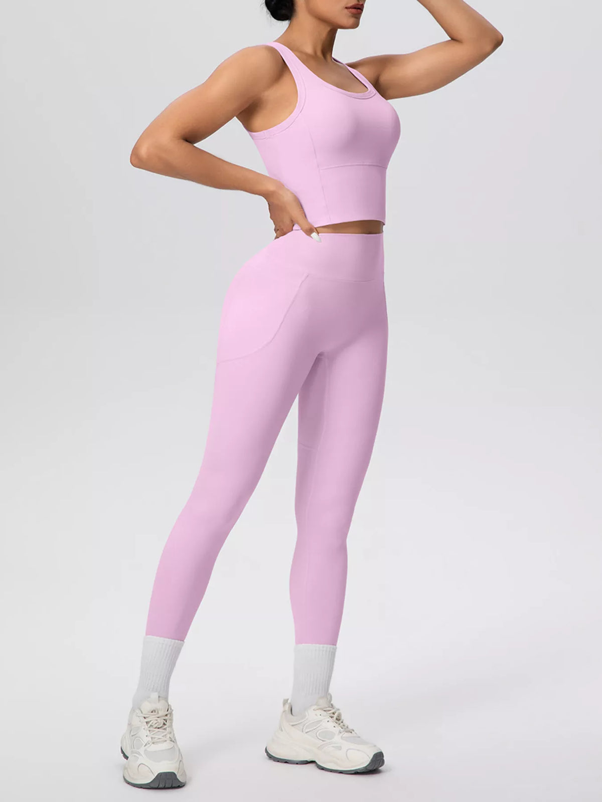 White tank and leggings posed from the side with one arm raised