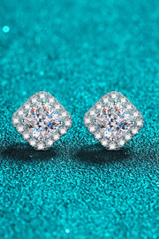 Square clear-stone cluster stud earrings positioned diagonally on a teal background