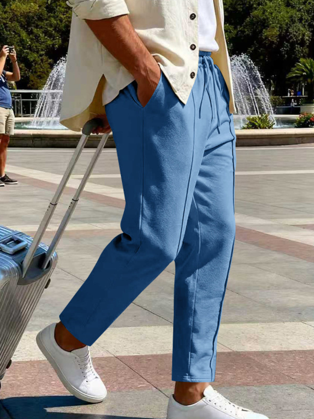 Light blue pants styled with a light overshirt beside a suitcase.