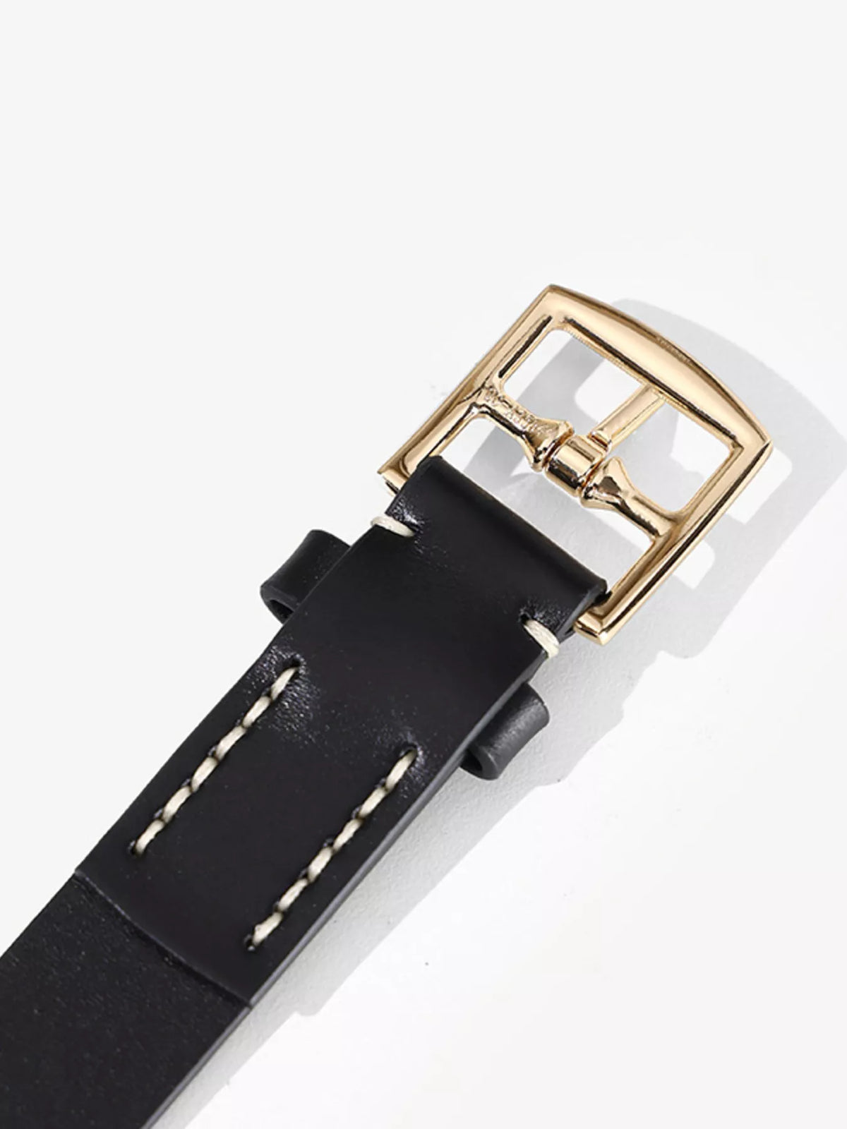Underside close-up of a black belt showing buckle attachment and pale stitching