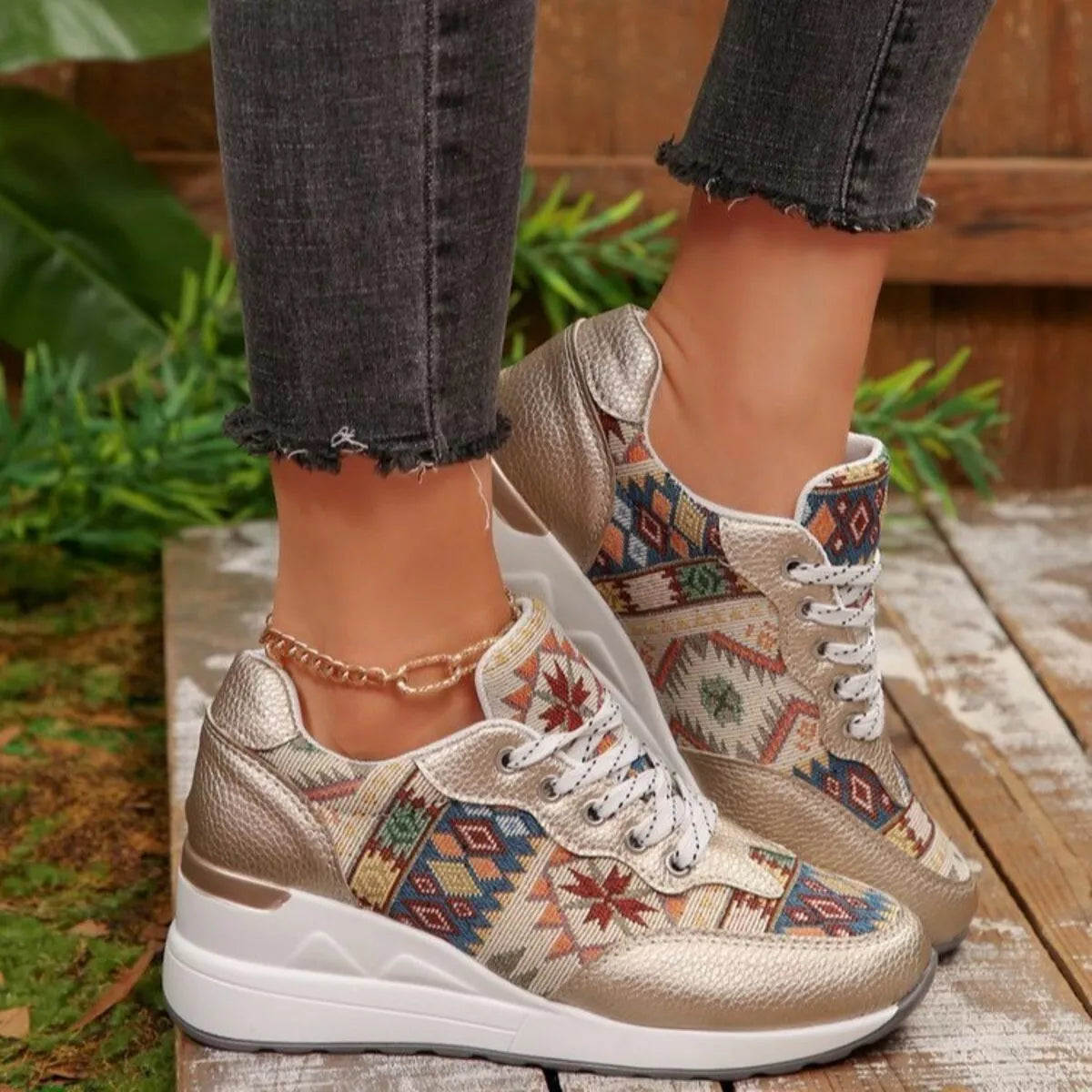 Close side view of patterned cream wedge sneaker worn with dark jeans