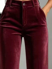 Close front view of burgundy velvet trousers showing the button waist and belt loops