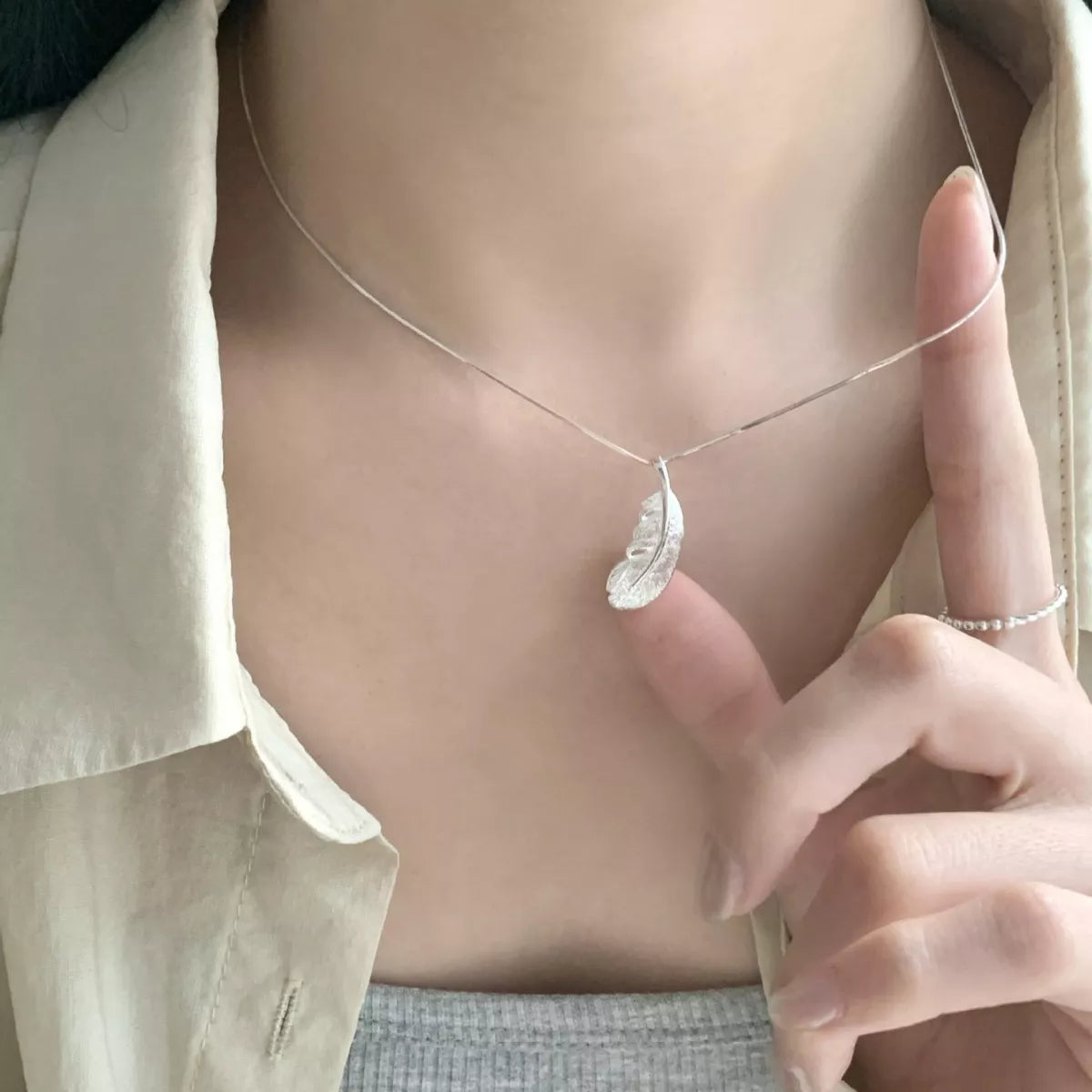 Close view of feather pendant held between fingers