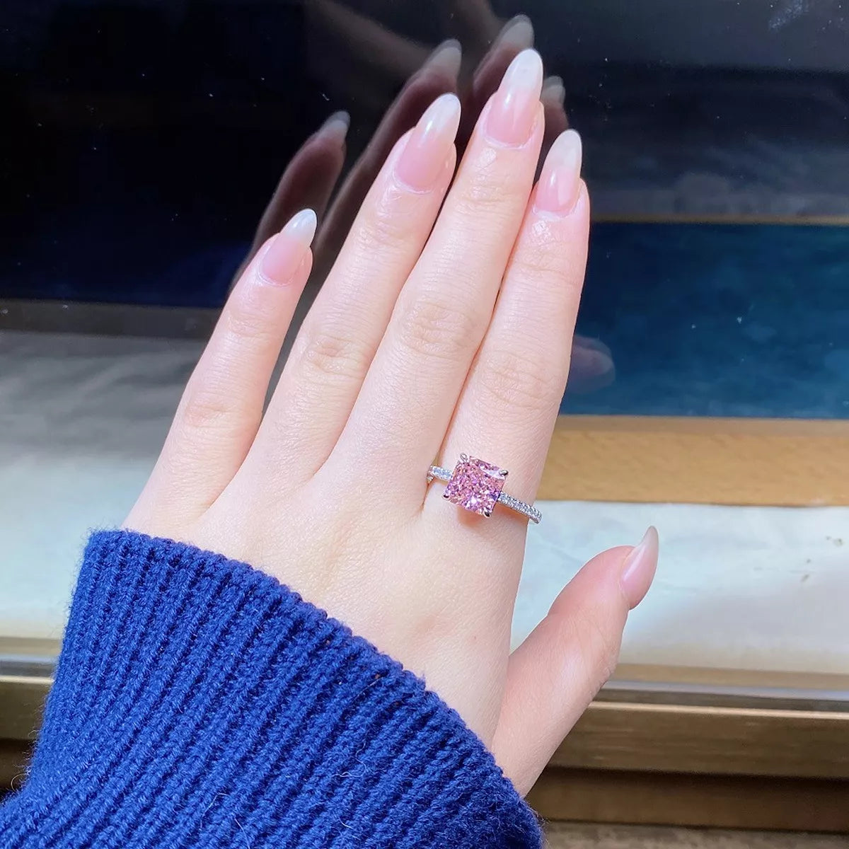 Close-up of pink square center stone on finger