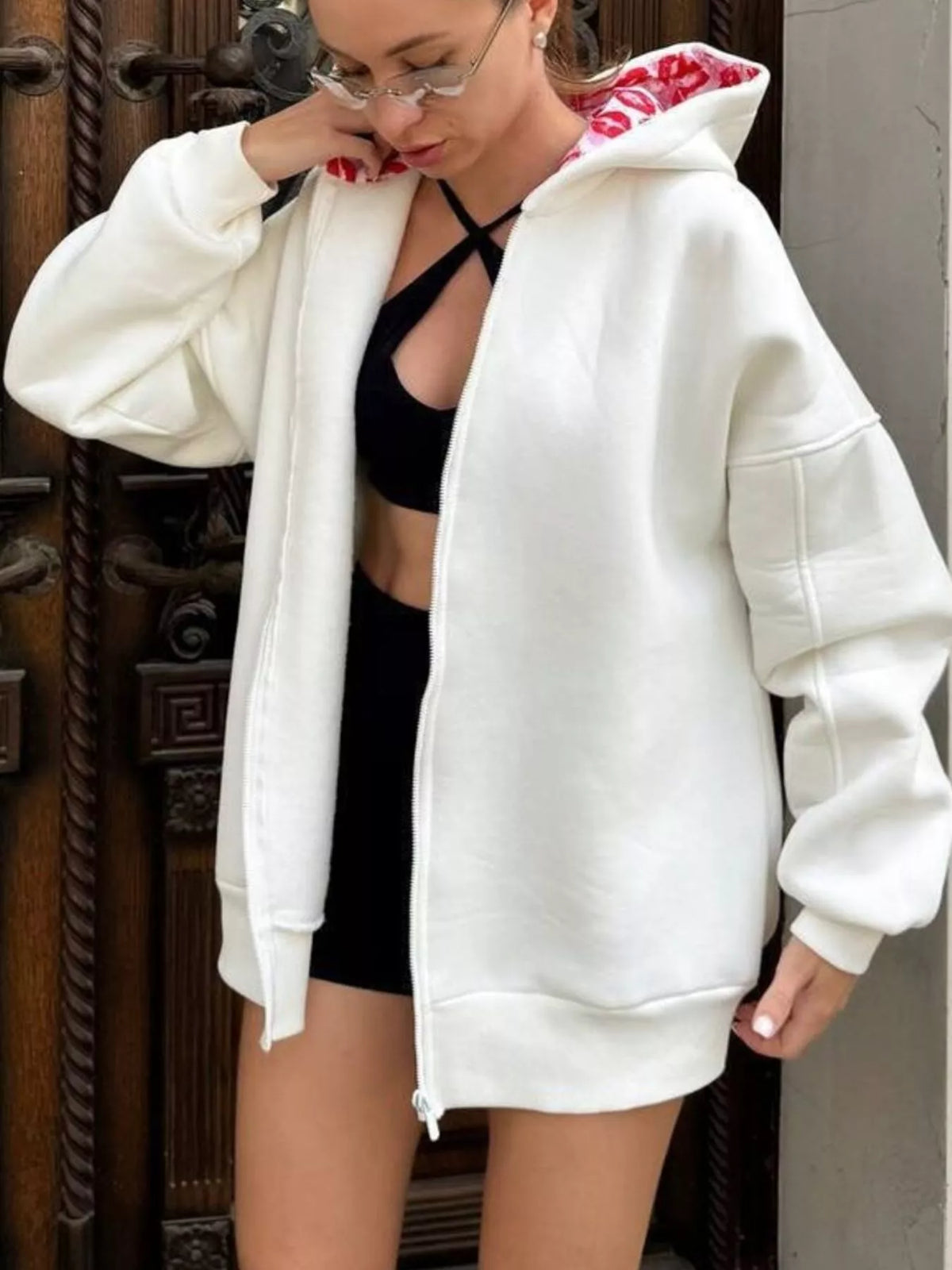 Front view of oversized white zip hoodie worn open, showing red lip-print hood lining