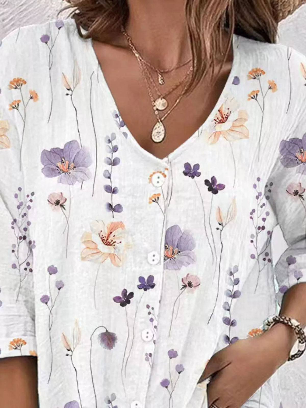Close-up of white blouse with pastel floral print and V-neck.