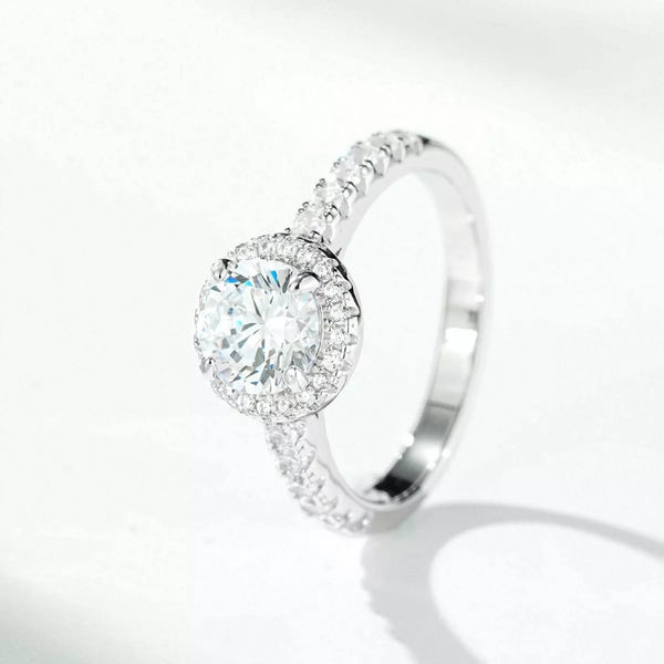 Angled side view of a round center stone ring with a halo and clear-stone shoulders