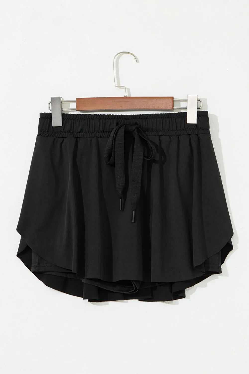 Black active skort shown from the back, with a wide elastic waistband and layered flounce
