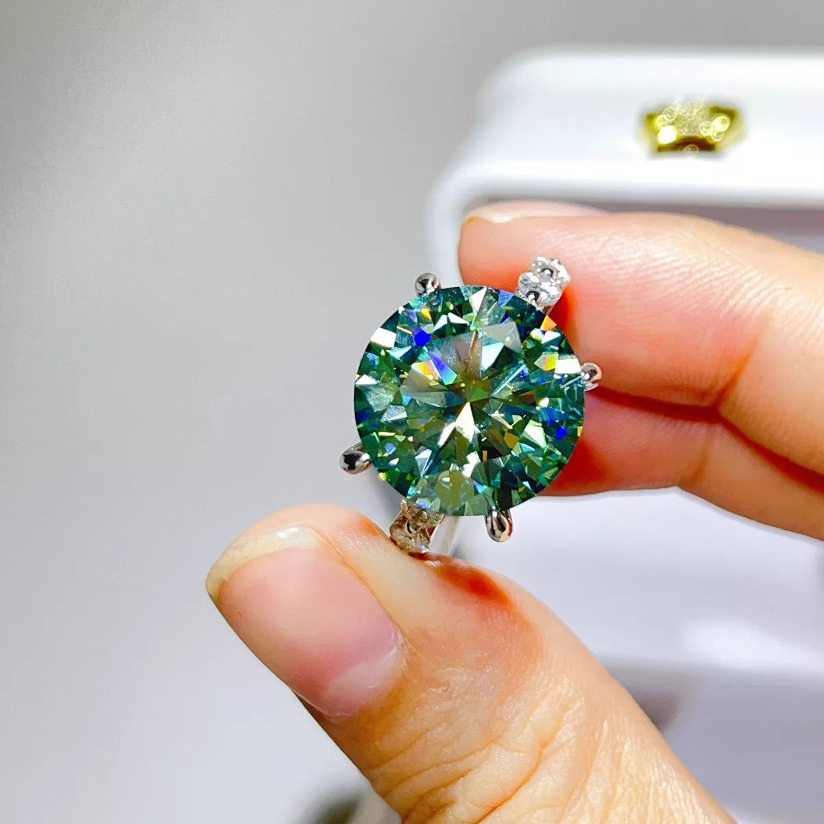 Close-up of green-blue centre stone ring held between fingers