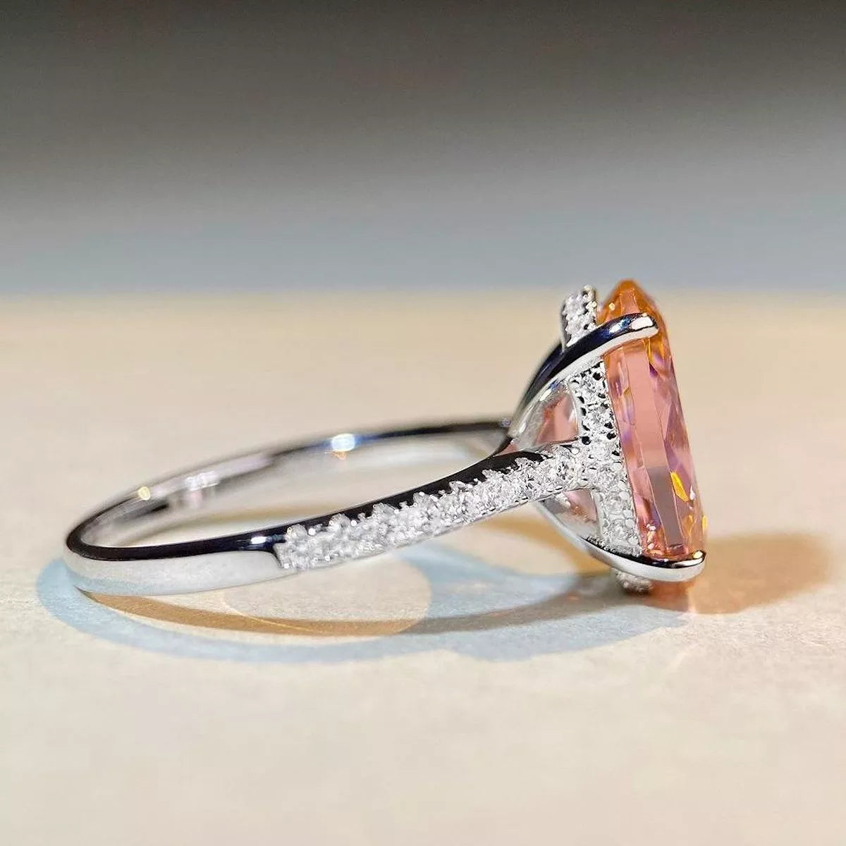 Side profile of the oval pink ring showing its raised setting and stone-set shoulders