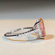 Side profile of the oval pink ring showing its raised setting and stone-set shoulders