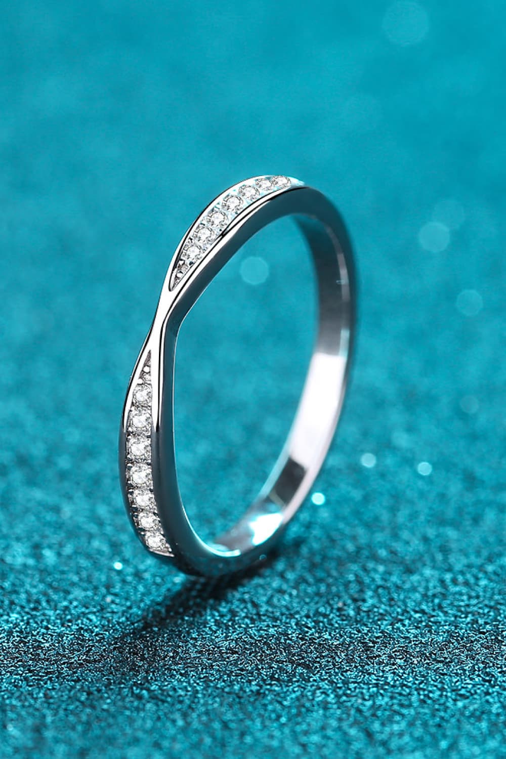 Front view of a slim pavé half-eternity ring standing on teal.