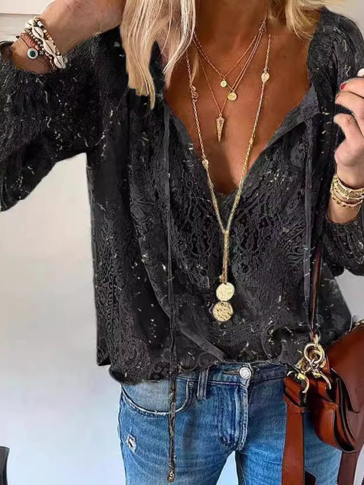 Close view of black blouse's sheer floral lace and front tie detail
