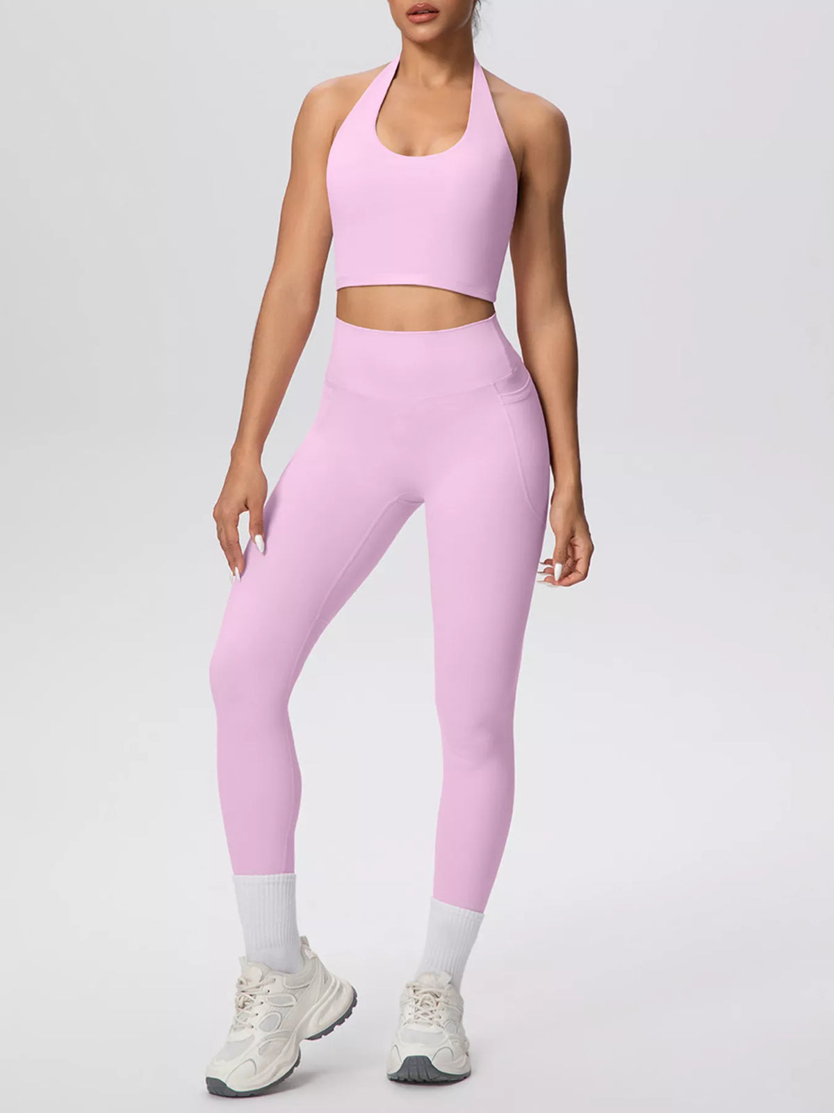 Model wearing pink halter crop top and leggings from the front