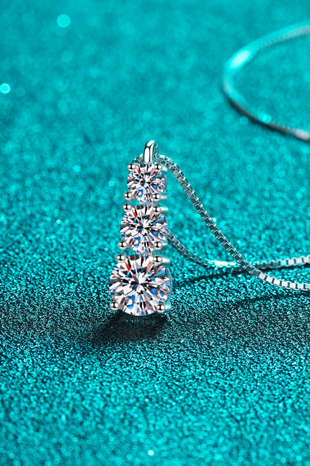 Side view of three clear stones set vertically on a silver necklace