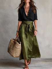 Model wearing a black button-down shirt and olive green tie-waist midi skirt.