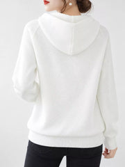 Back view of the white knit sweater showing its hood and ribbed hem.