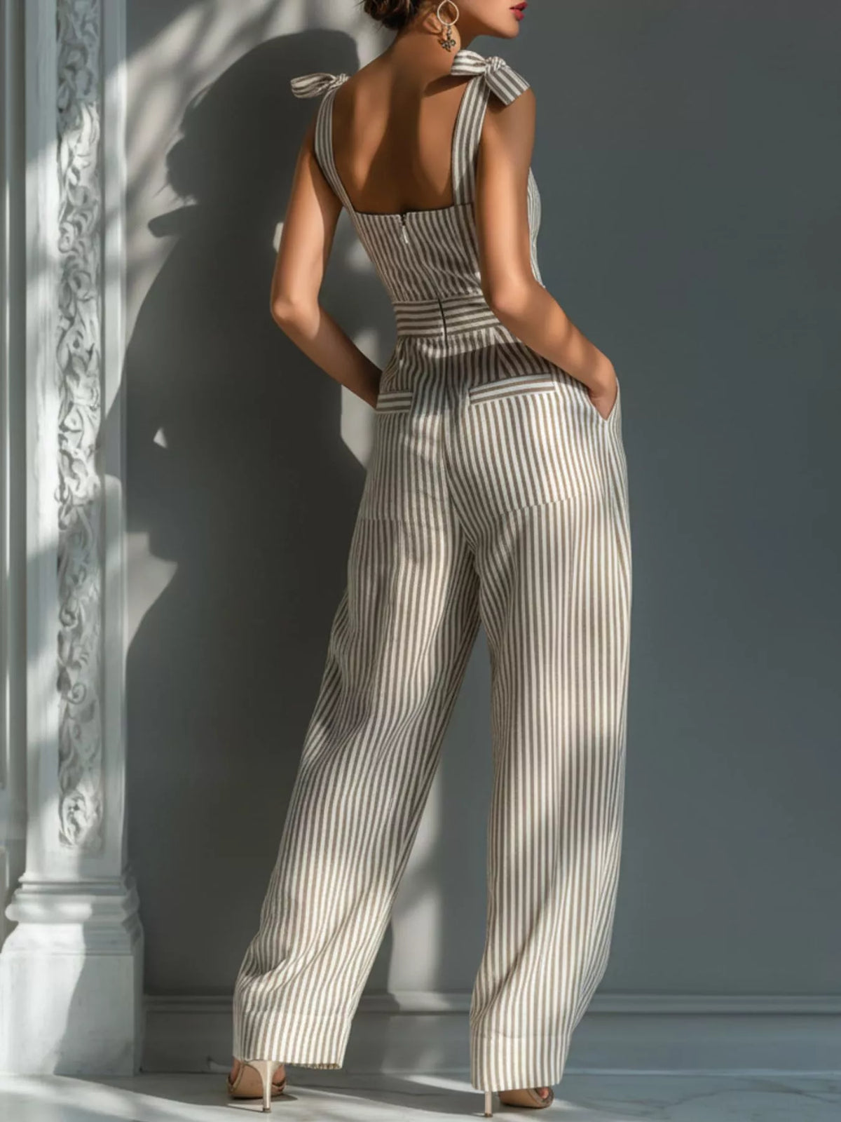 Back view of the striped jumpsuit showing its open back, tied straps and wide legs.