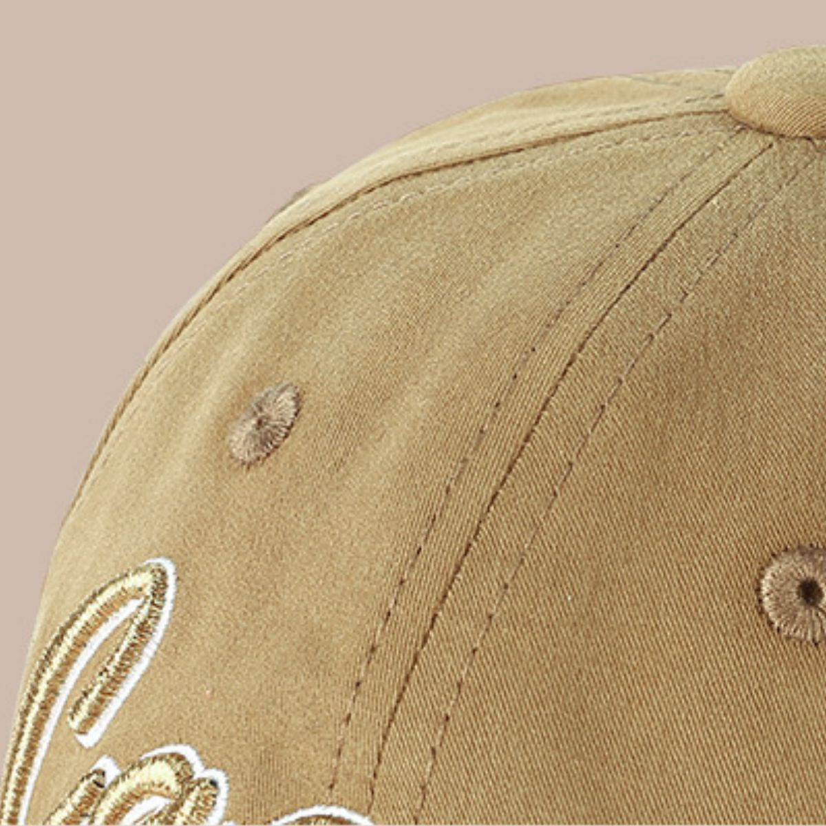 Close-up of khaki baseball cap showing stitched crown panels, embroidered eyelets and part of the front embroidery