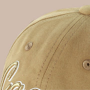 Close-up of khaki baseball cap showing stitched crown panels, embroidered eyelets and part of the front embroidery