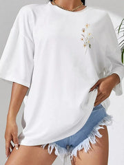 Front view of white oversized tee with small floral chest motif and denim shorts