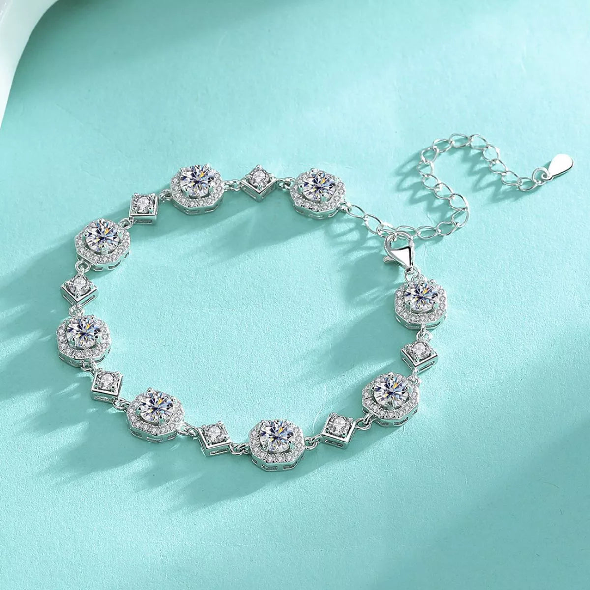 Silver-tone moissanite bracelet arranged in a circle on turquoise fabric