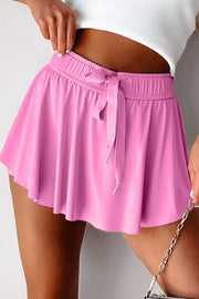 Bright pink high-waist skort with long front drawstring, close view.