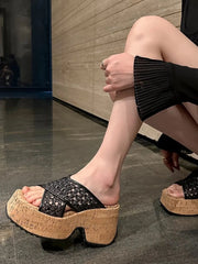 Black open-weave cross-strap sandal with cork-look platform sole, side view on a foot