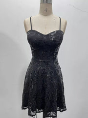 Black floral-sequin mini dress displayed on a dress form against a pale wall.