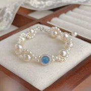 Pearl bracelet with blue center stone displayed on a cushion