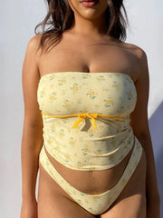Front view of a pale yellow floral tube top and matching high-cut bottoms, modeled outdoors.