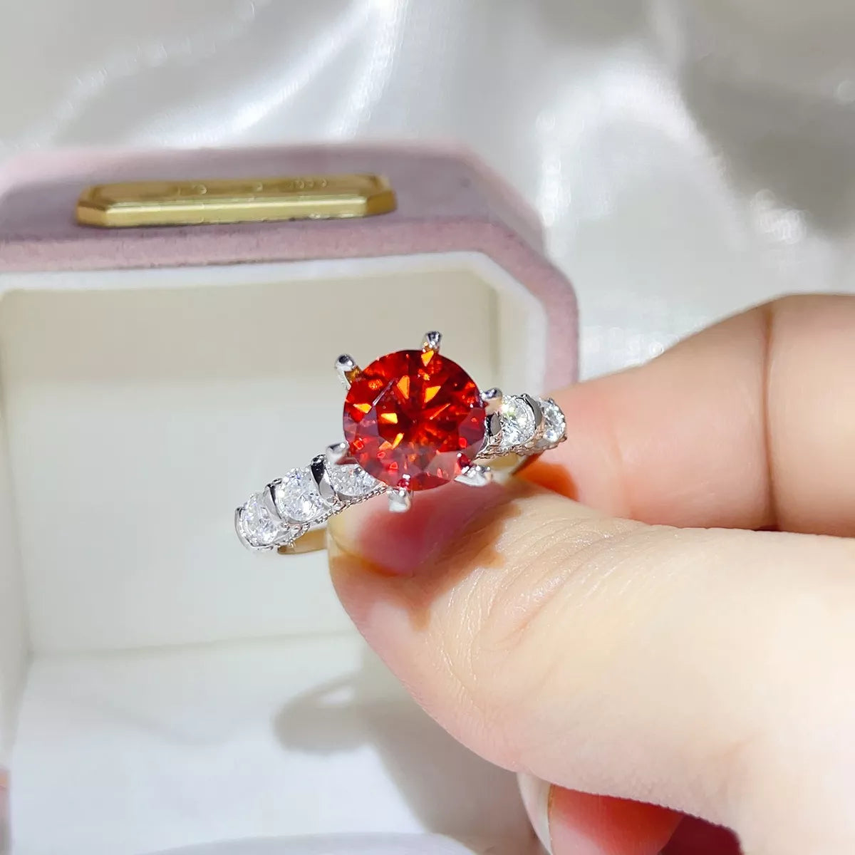 Side view of a three-carat red-orange moissanite ring with clear stones