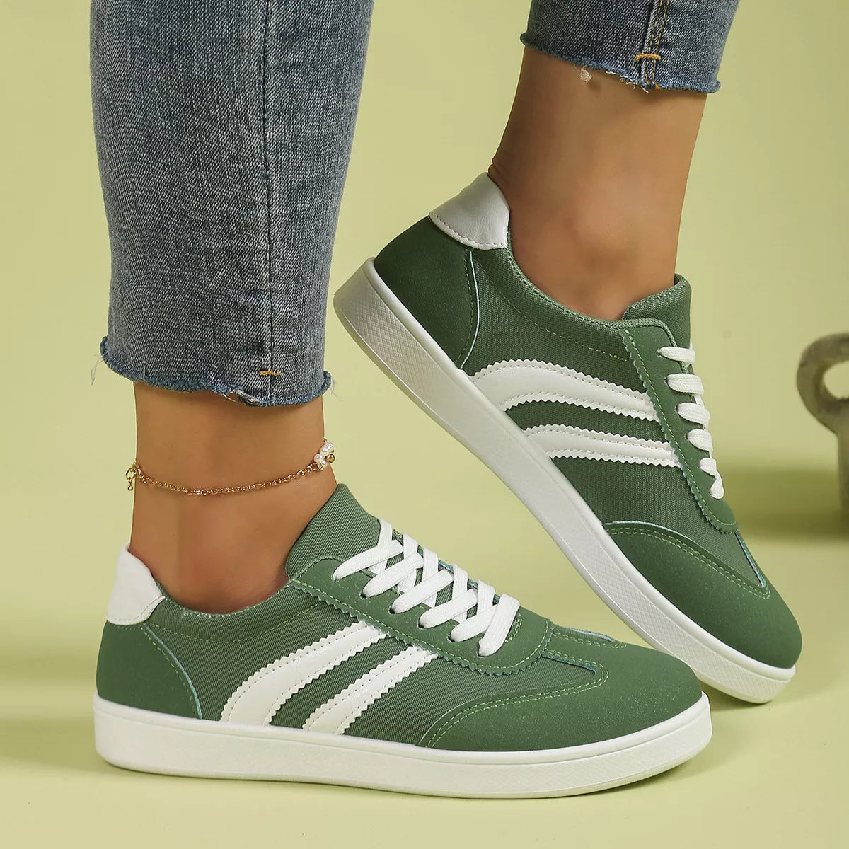 Green flat shoes with white stripes worn in side view
