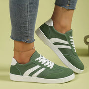 Green flat shoes with white stripes worn in side view