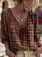 Model wearing the blouse in brown with dark spots, ruffled V-neck and three-quarter sleeves