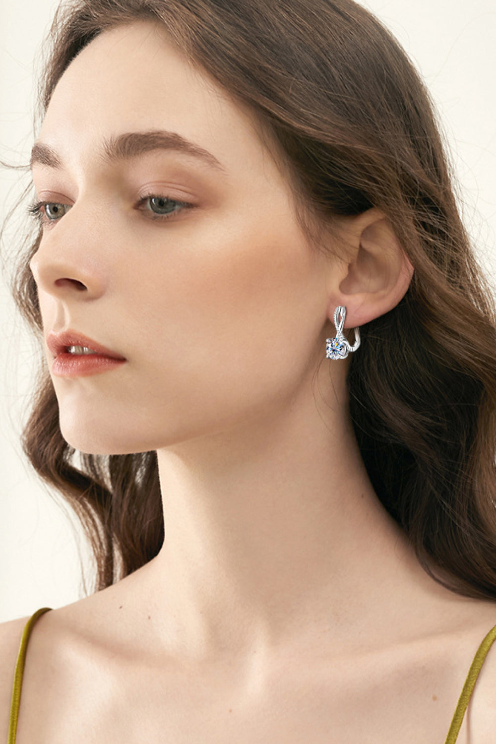 Side portrait of a model wearing silver-tone round-stone drop earrings