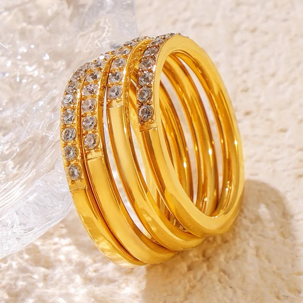 Stack of gold-tone zircon rings displayed on a textured surface