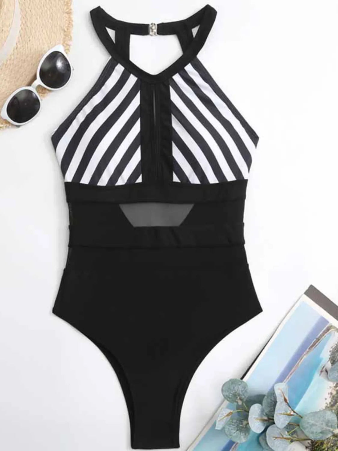 Black swimsuit with wide white diagonal stripes laid flat, showing the keyhole and sheer waist panels