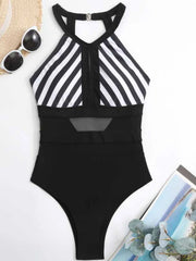 Black swimsuit with wide white diagonal stripes laid flat, showing the keyhole and sheer waist panels
