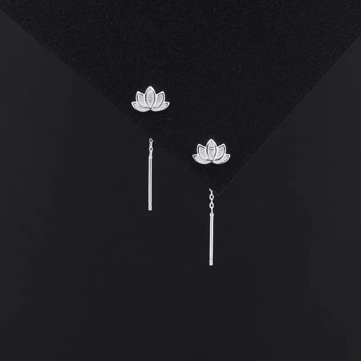 Pair of lotus stud earrings with slim drop bars on dark display