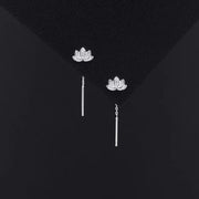 Pair of lotus stud earrings with slim drop bars on dark display
