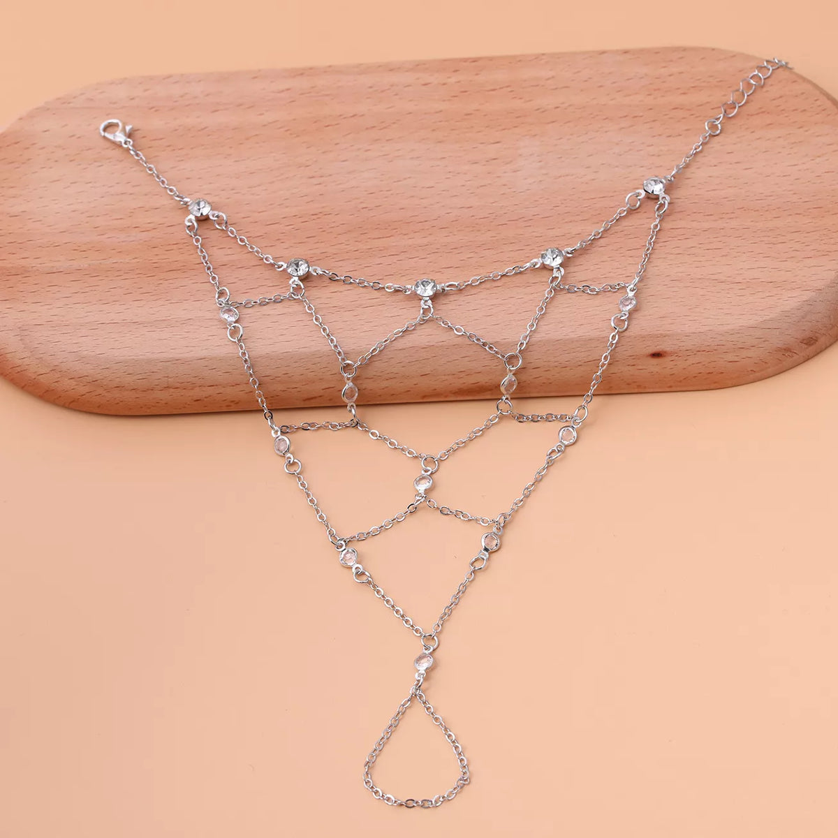 Gold-tone connected hand chain displayed across a wooden surface